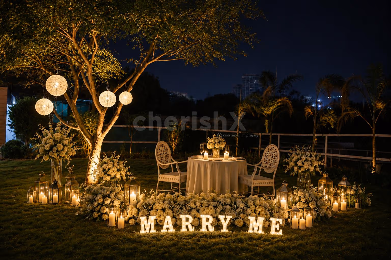 candlelight proposal setup with white floral arrangements on a lush lawn, creating a timeless romantic ambiance.