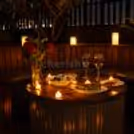 Romantic terrace candlelight dinner with wooden furniture and private outdoor setting.