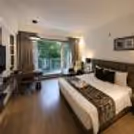 Romantic stay in Gurugram with a luxury hotel room having a king-size bed, work desk and balcony.