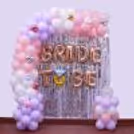 A shiny silver background with bride-to-be foil letter balloons and pastel bachelorette balloon decoration.