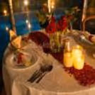 Beautifully decorated couple dining table with rose petals and warm candlelight.