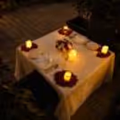 Romantic evening arrangement with dinner, table decoration, candles, rose petals and decorative lights.