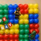 Custom Name Displayed On A Colourful Building Block Themed Wall Made With Red, Blue, Green And Yellow Balloons.