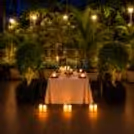 Private dining area setup for a candlelight dinner. The setting is a natural garden.