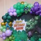Closeup of a Hulk theme balloon arch with green and purple balloons for kids birthday party.