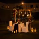Romantic outdoor candlelight dinner setup with elegant floral décor, warm lanterns, and a luxury dining table in a garden setting.