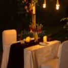 Elegant candlelit dinner under the stars with floral arrangements, hanging lights, and a romantic atmosphere.