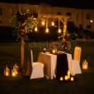 Luxury proposal and anniversary dinner arrangement with roses, lanterns, candlelight, and sophisticated garden décor.