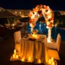 Romantic poolside dinner setup with balloon arch, candlelight, and luxury outdoor dining décor.