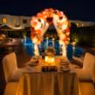 Luxury candlelight date night by the pool with floral balloon arch and elegant table setting.
