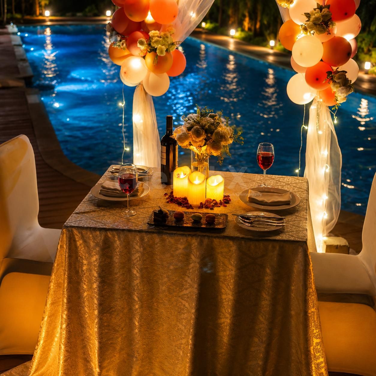 Outdoor candlelit dining experience with illuminated balloon arch and luxury event styling.