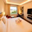 Spacious hotel room with king-size bed, warm lighting, modern interiors, and garden views, perfect for a relaxing daycation.
