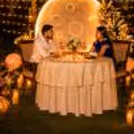 Couple enjoying a private moonlit candlelight dinner with floral décor, glowing candles, and a giant illuminated moon backdrop at Umrao.