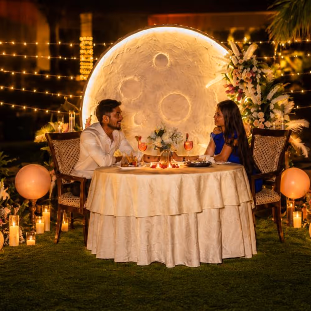Luxe Moonlit Candlelight Dinner by Umrao showcasing a romantic private dining setup with candles, flowers, fairy lights, and a glowing moon backdrop.