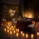 Romantic table setup for a proposal dinner featuring a glowing “Marry Me” background, table setup, and floor candles