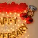 A picture-perfect backdrop is adorned with delicate roses, twinkling fairy lights, and heart-shaped foil balloons, setting the space for an unforgettable celebration.
