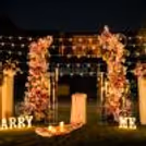 Candlelight dinner table for a special couple celebration, fairy lights and romantic lawn decorations, floral arch.