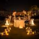 Fairy lights, lovely candlelit floral couple's dinner with a hatted dining table on a lawn
