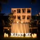Romantic candlelit dining table and personalized memory photo wall & beautiful flowers for couples.
