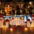 Romantic poolside dining setup with glowing LOVE letters, red rose décor, candles, and illuminated fountains creating a luxurious outdoor dining experience.
