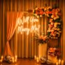 Lovely romantic proposal setting in an air-conditioned cabana, decorated with flowers and a bright neon sign.