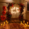 Romantic Setting With Red Flowered Arch, Neon Message, Candles And Petals.