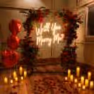 Romantic Setting With Red Flowered Arch, Neon Message, Candles And Petals.