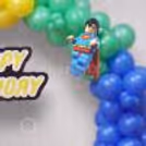 A Birthday Ring With Blue Balloons, Thematic Decorations And Personal Name Signs From The Side.