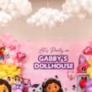 Close-up of Gabby's Dollhouse birthday setup, themed with a banner, balloon columns and character setup.