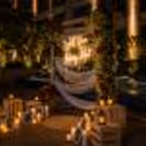 Romance Poolside Proposal Decor With Neon Sign 'Will You Marry Me? White sheer drapes, floral pillars and LED candles included.