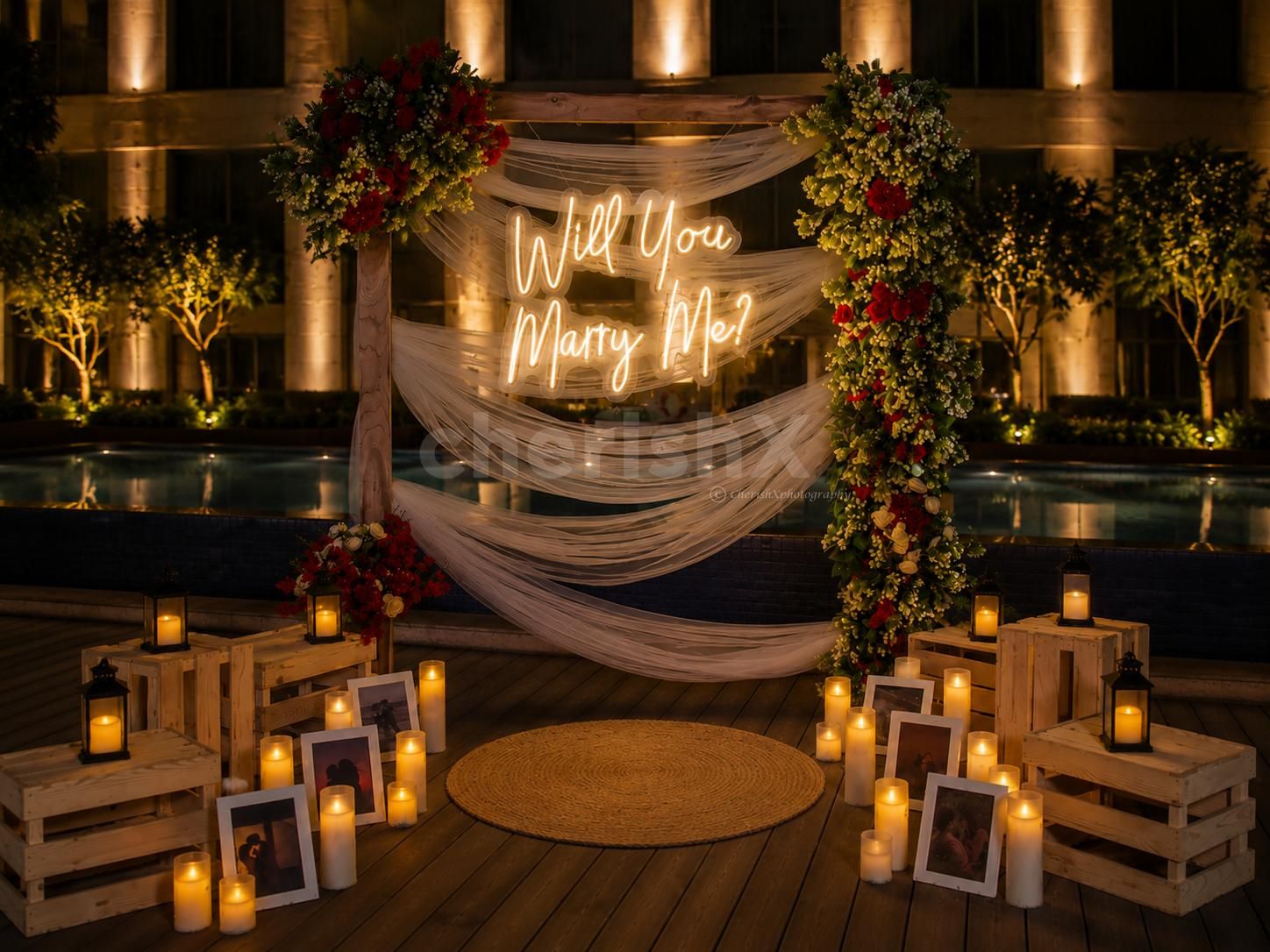 Romantic luxury proposal by the pool with candles, fresh flowers, cake, bouquet, and fine dining ambience.