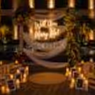 Romantic proposal flowers, white curtains, lighted candles and framed photos by the pool. Evening. Scene.