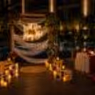 Gorgeous flowers, wood crates, and warm candlelight for a poolside proposal setup