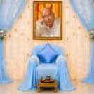 Attractive Seating Area Featuring A Blue Satin Cushion And A Golden Chowki In Front Of The Prayer Area.