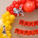 Red, yellow and blue balloon garland with Beyblade character cutouts and birthday banner.