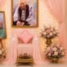 A Soft Pink Stage Setting With A Golden Vase Of Artificial Roses Beside A Seat.