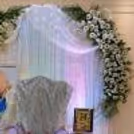 Elegant Guru Ji celebrating devotion with greenery and a soft LED curtain light wall.