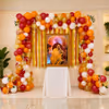 Colourful Balloon Arch With Hanging Strings Of Marigolds Around A Framed Spiritual Portrait On A White-Covered Table.