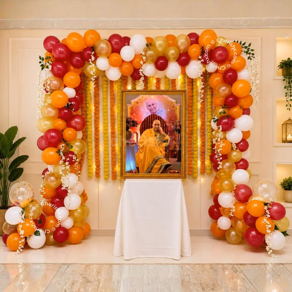 Colourful Balloon Arch With Hanging Strings Of Marigolds Around A Framed Spiritual Portrait On A White-Covered Table.