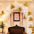The balloon arch of CherishX's Guruji Birthday Decor is made with white. golden chrome and Golden Confetti balloons.