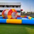 Side angle of inflatable water zorbing activity and floating roller on water-filled playground.