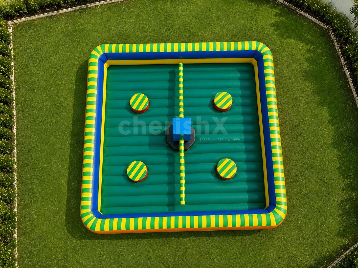 Professional outdoor setup of an inflatable Obstacle Eliminator game with four player stations, rotating obstacle poles, and a premium inflatable arena for parties and family events.