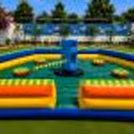 Top view of children's inflatable obstacle playground with central rotating challenge and balancing platforms.