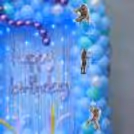 Silver 'Happy Birthday' Cursive Letters On A Glittery Curtain With Led Lights.