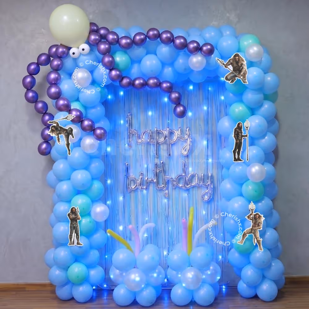 Party Lighting And Pastel Balloon Clusters Frame A Blue Fringe Backdrop With A Curved Shape.