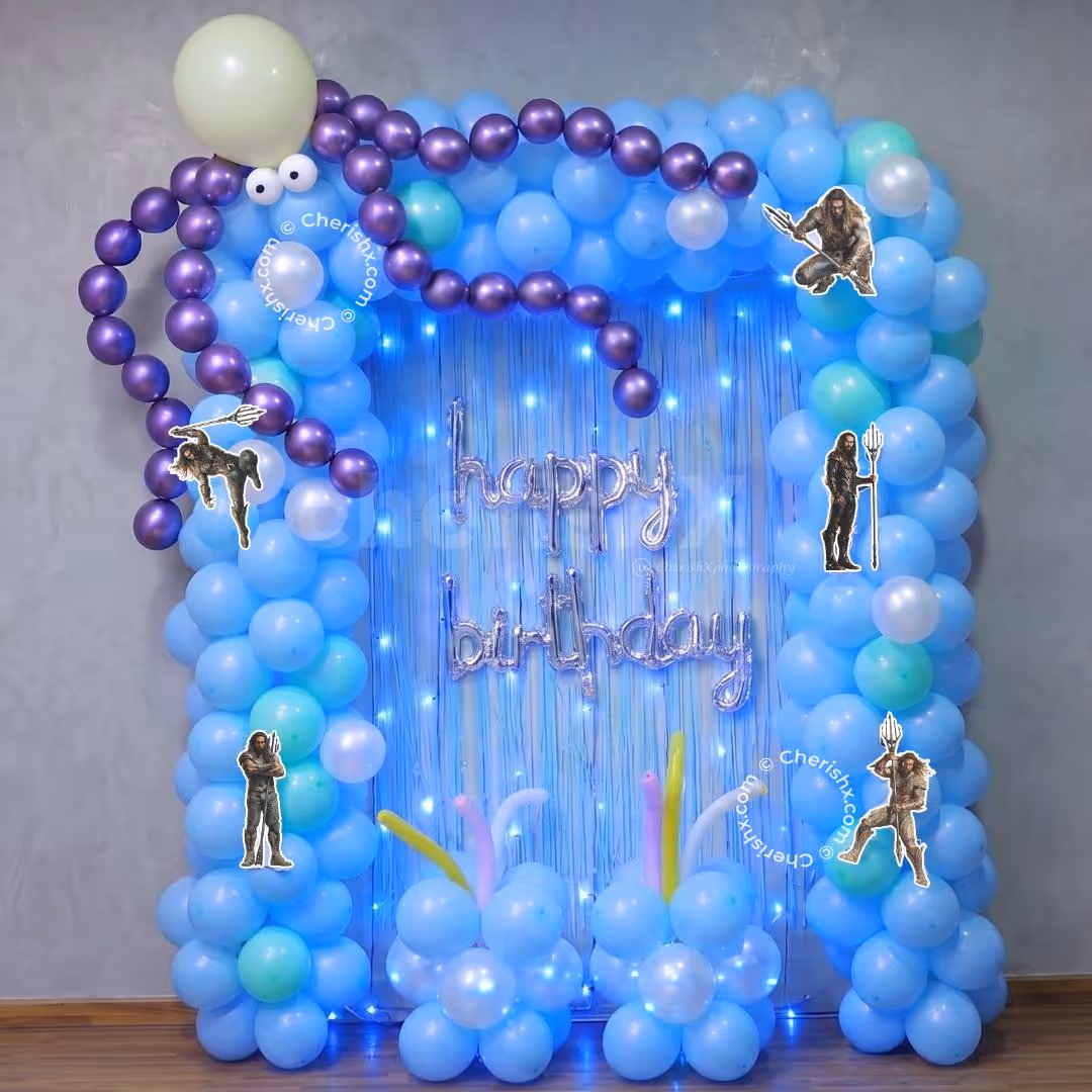 Party Lighting And Pastel Balloon Clusters Frame A Blue Fringe Backdrop With A Curved Shape.