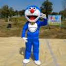 Life-size Doraemon mascot entertaining children at a birthday party with vibrant outdoor event décor, creating a fun and memorable celebration experience.