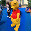 Yellow bear mascot entertaining children at a fun-filled outdoor event with vibrant party décor.