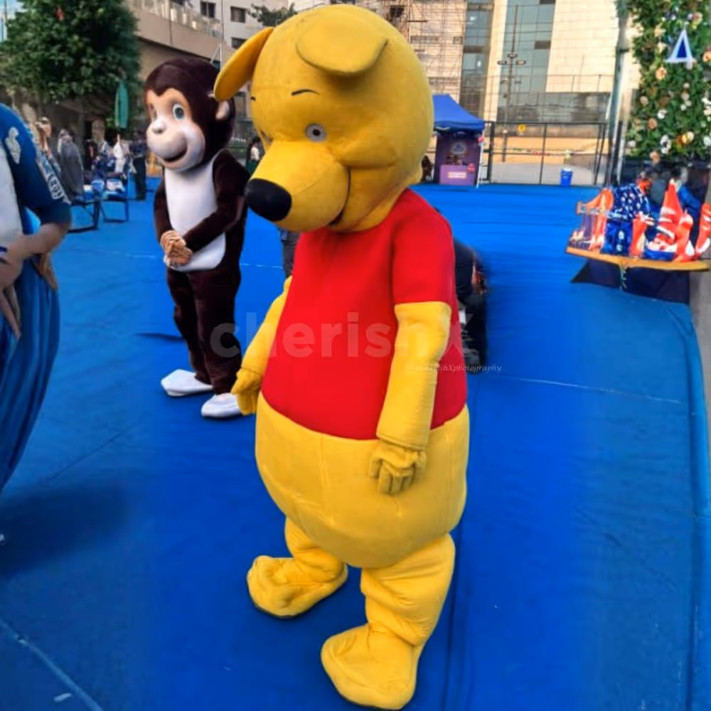 Yellow bear mascot entertaining children at a fun-filled outdoor event with vibrant party décor.