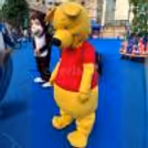 Yellow bear mascot entertaining children at a fun-filled outdoor event with vibrant party décor.